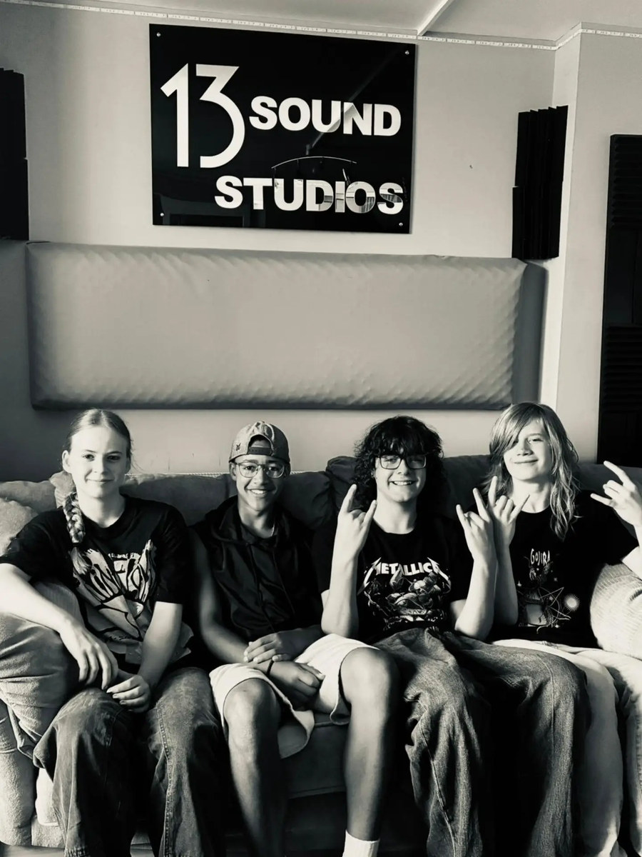 The four of them sat along a sofa at 13 Sound Studios, throwing horns, under the studio's sign.